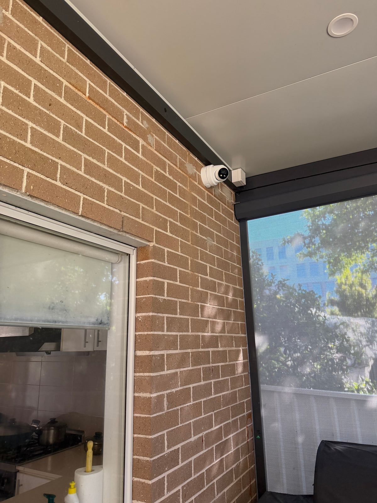 DS-2CD2387G3-LIS2UY/SL real installation - wider view of the white turret camera installed beneath a covered patio; camera installation example, not the full kit contents