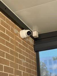 DS-2CD2387G3-LIS2UY/SL real installation - close-up of the white turret camera and junction box beneath a covered patio; camera installation example, not the full kit contents
